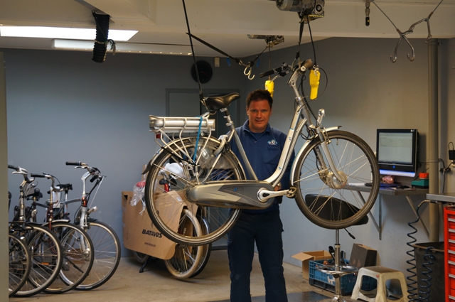 Monteur tilt een e-bike omhoog in de werkplaats