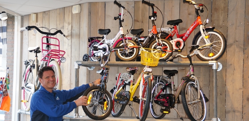 Een medewerker hangt kinderfietsen aan de wand