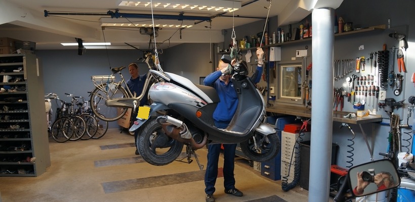 De werkplaats met een scooter op de brug en de gereedschapswand